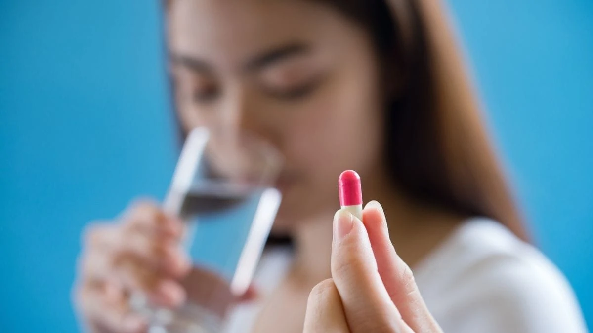mulher bebendo agua segurando ansiolitico